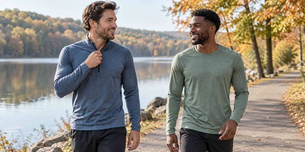 Two men beside an autumn lakeside running trail wearing a quarter-zip top and a long-sleeve crewneck shirt